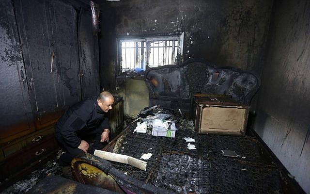 A Palestinian police member inspects the damage inside a burned-out house belonging to a key witness to an arson attack last year by Jewish extremists that killed a Palestinian family, in the West Bank village of Duma, after fire broke out in the home in the early hours of March 20, 2016. (AFP/Jaafar Ashtiyeh)
